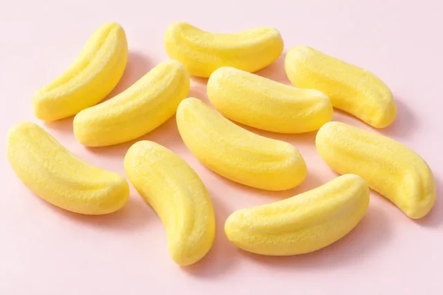 Foam Bananas. Foam banana sweets, curved like a small banana, pale yellow, soft and airy with a matt, fine powdery surface.